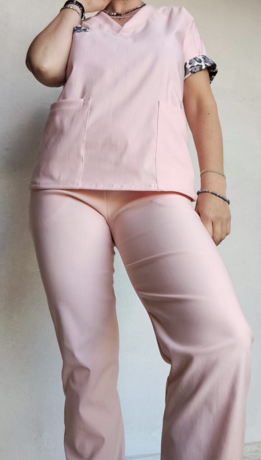 Mujer con uniforme rosa posando. El uniforme tiene ribete de estampado de guepardo en las mangas. Fondo claro.