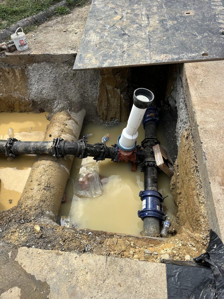 A bunch of pipes are sitting in a hole in the ground.