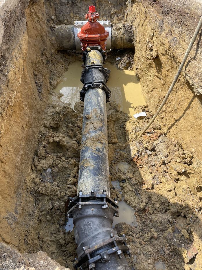 A water pipe is laying in the dirt in a trench.