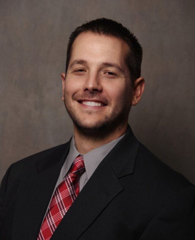 A man in a suit and tie is smiling for the camera
