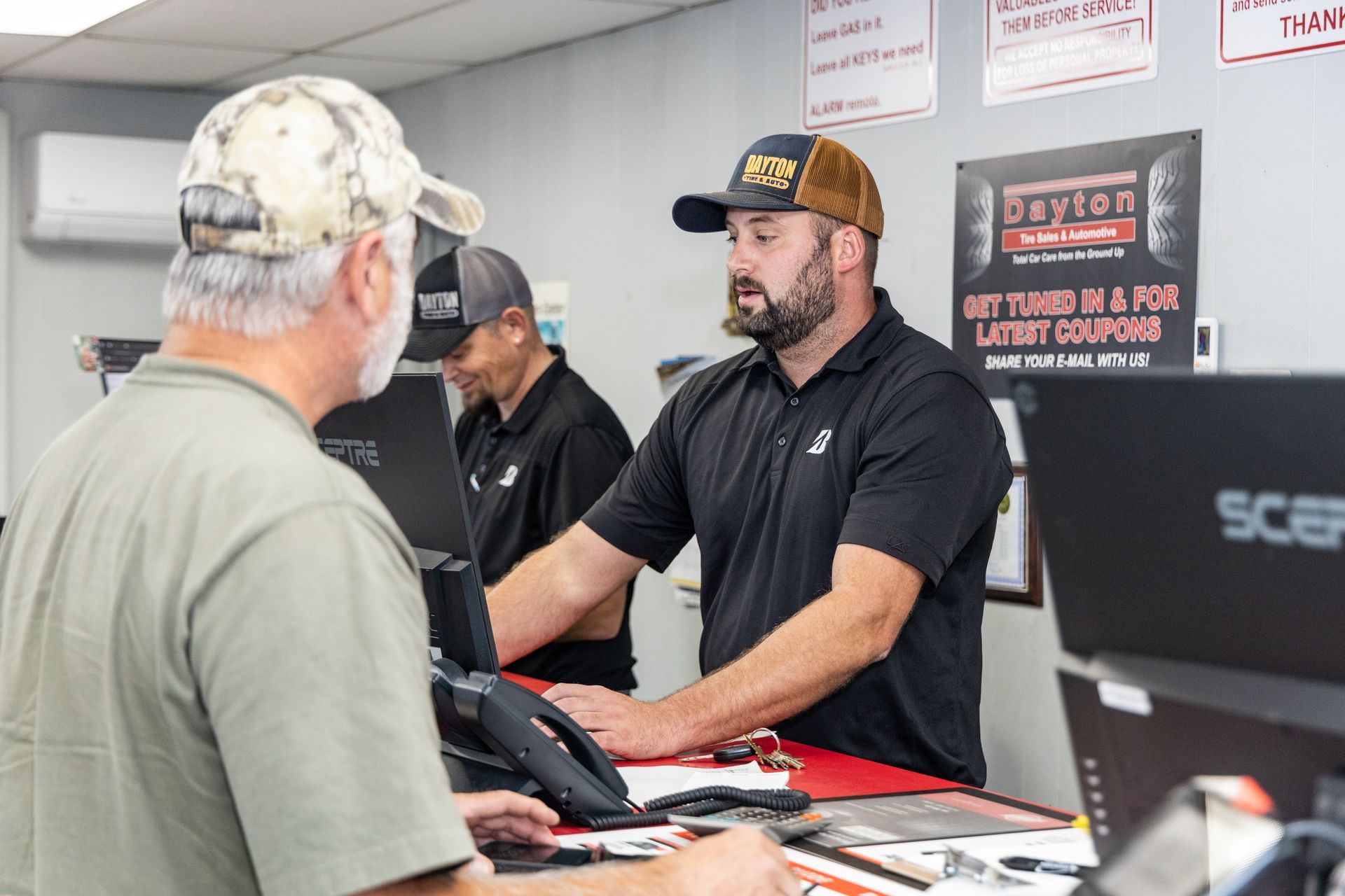 Woman reading on a black sofa in an auto shop waiting room | Dayton Tire & Auto