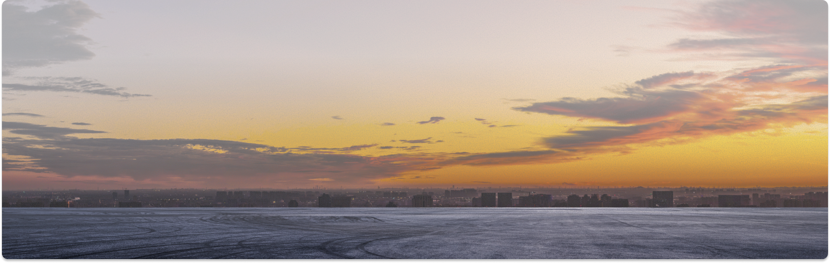 Sunset over a city skyline and water, with colorful sky reflecting on the water | Dayton Tire & Auto