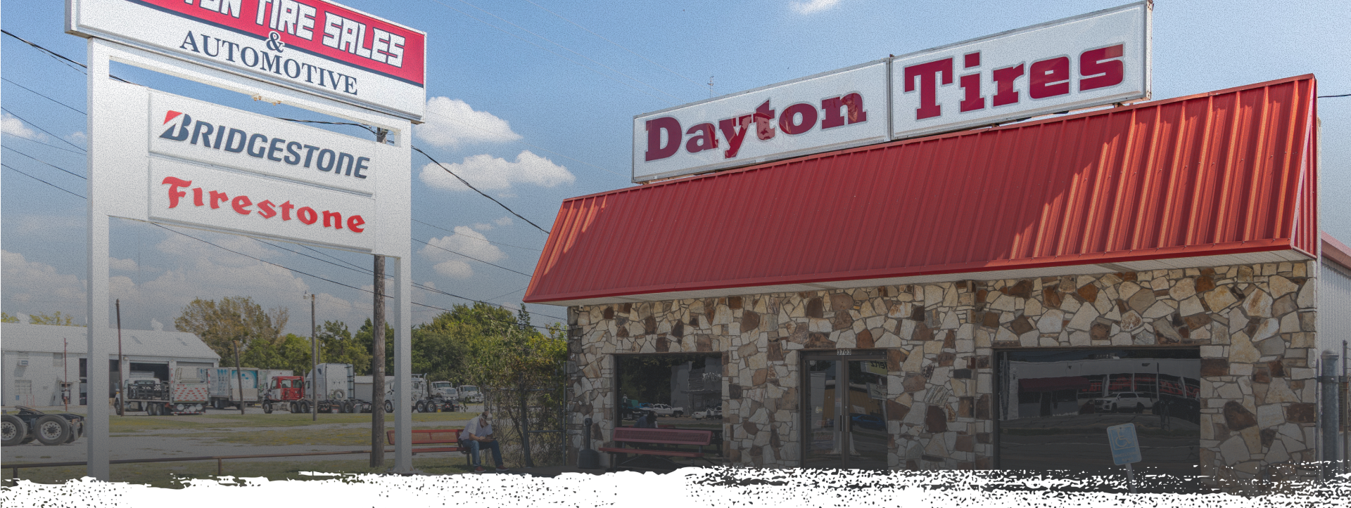 Dayton Tires store with a red roof and stone facade, and a sign displaying Bridgestone and Firestone tires  | Dayton Tire & Auto