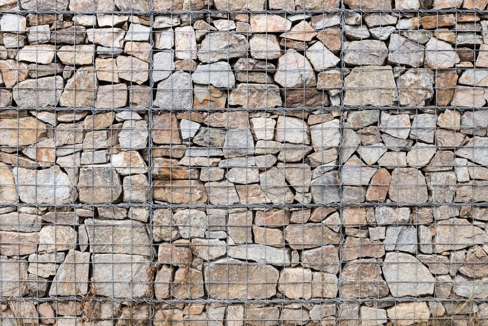 Stone Wall Constructed With Rocks Held Within a Wire Mesh Grid — Carl Whelan Building & Renovations In Wyong, NSW