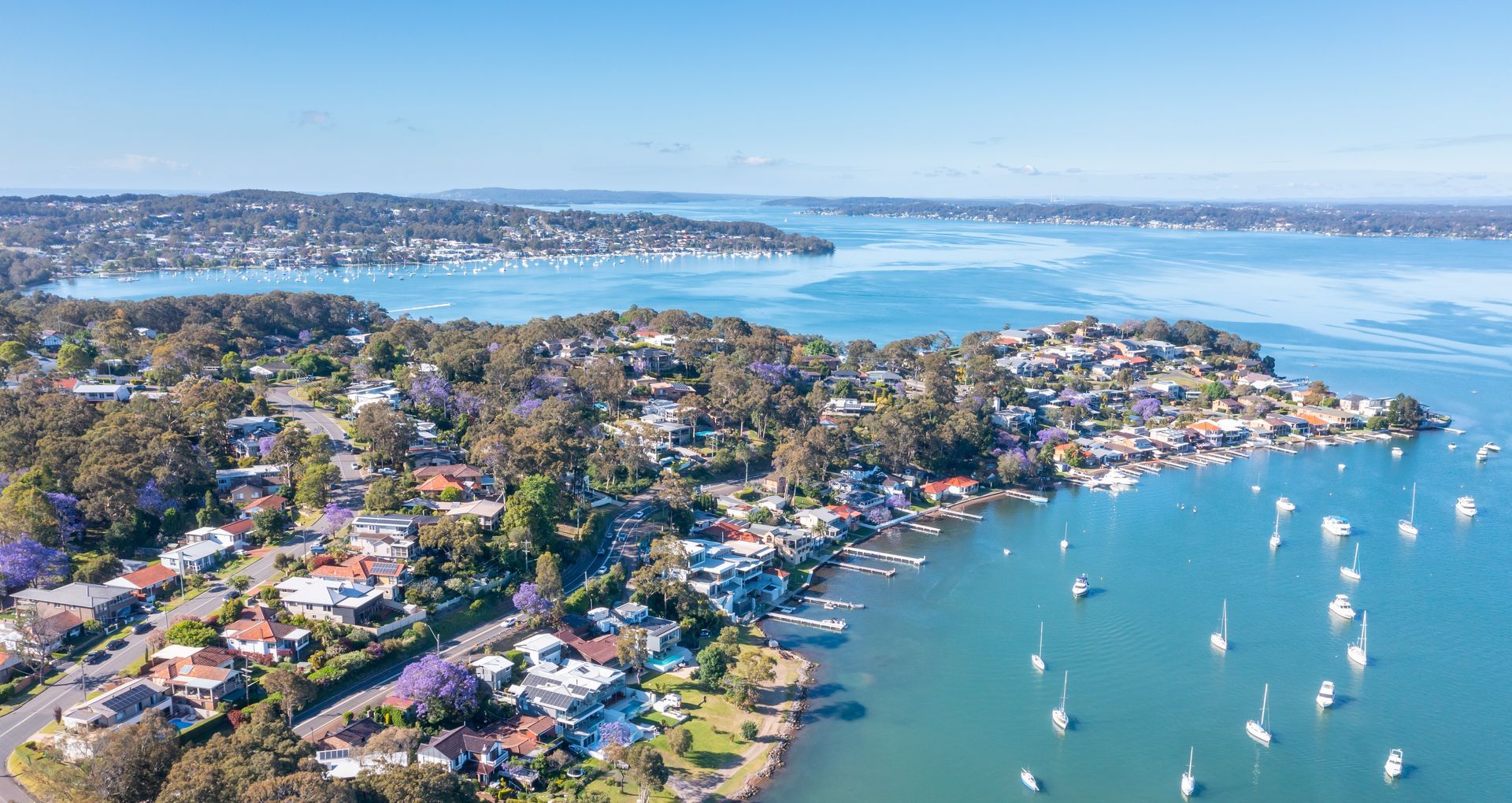 Aerial View of a Coastal Town With Houses, Boats, and Blue Water — Carl Whelan Building & Renovations In Lake Macquarie, NSW