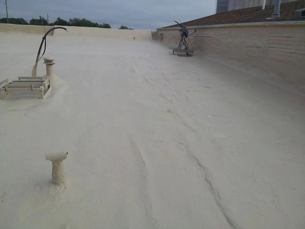 A man is spraying foam on the roof of a building.