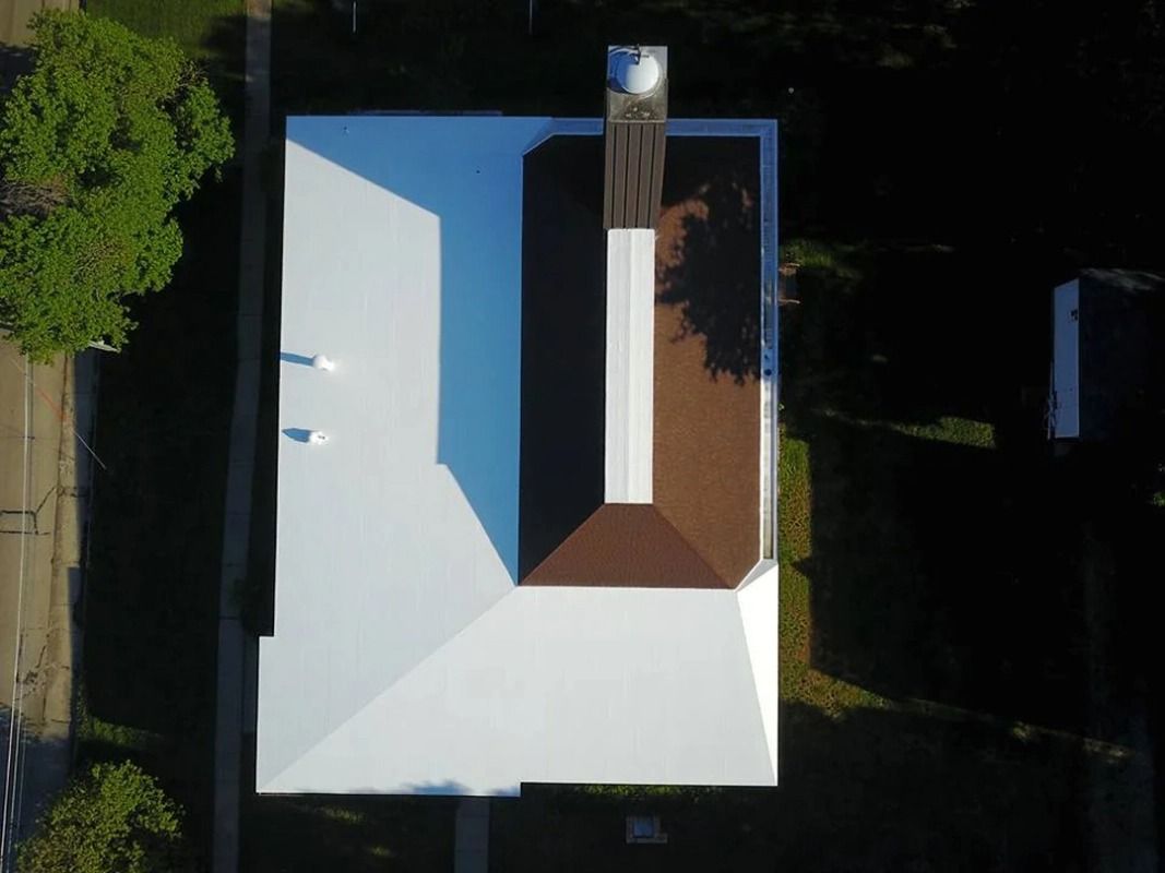 An aerial view of a house with a white roof and a brown roof.