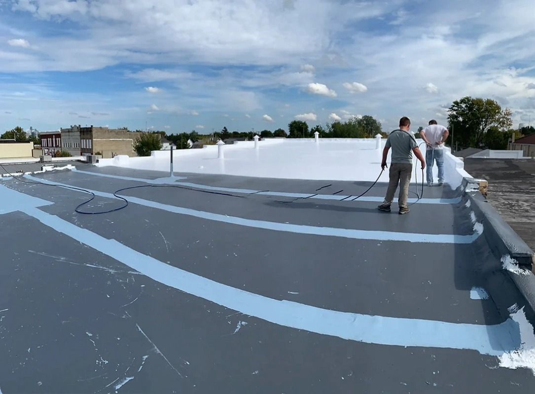 Two men are painting a roof with a roller.