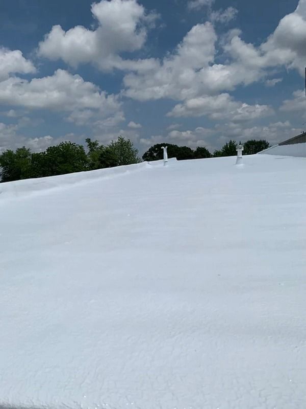 A white roof with a blue sky and clouds in the background.