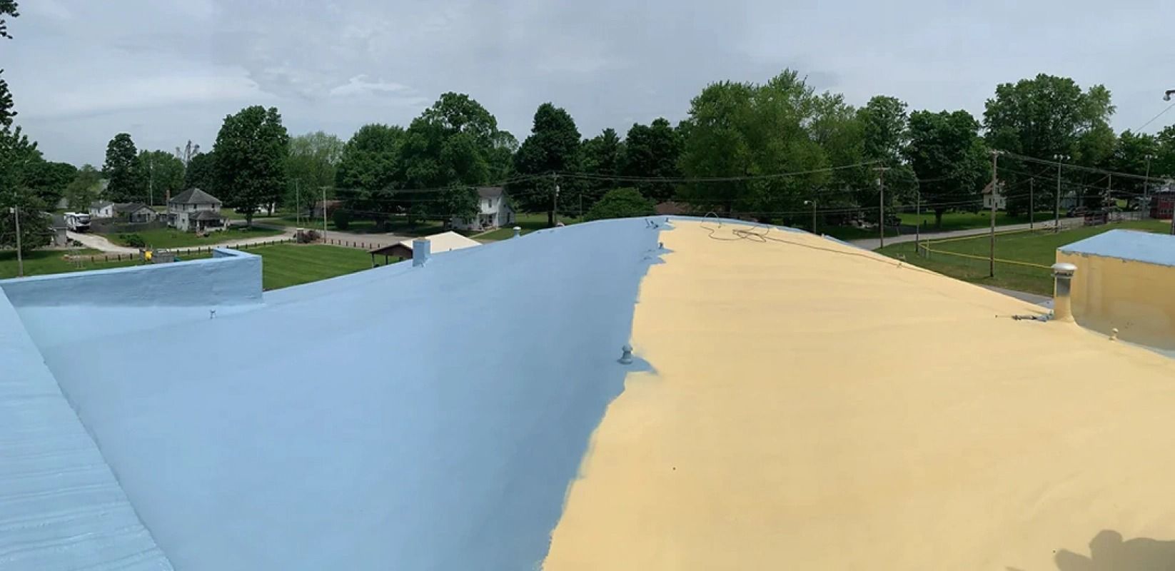 A blue and yellow roof with trees in the background.