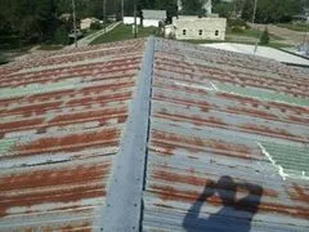 A rusty metal roof with a shadow of a person on it.