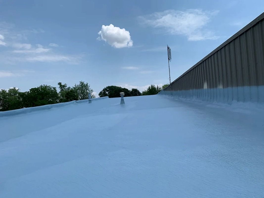 A roof with a blue coating on it and a blue sky in the background.