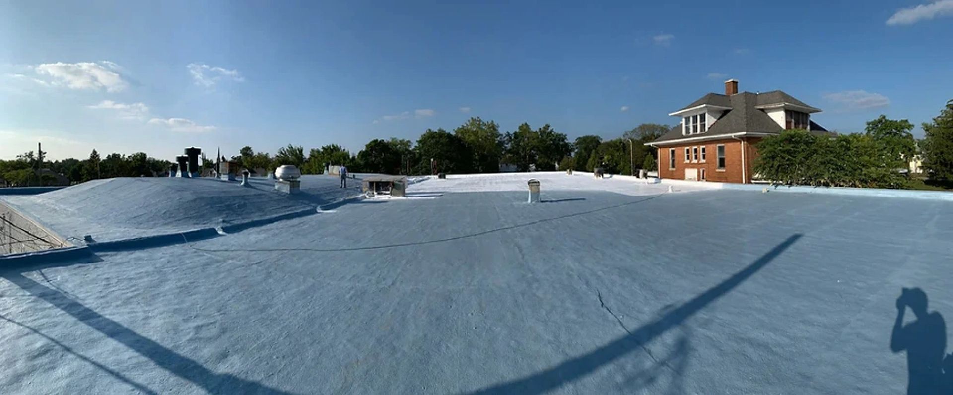 A large house with a white roof and trees in the background