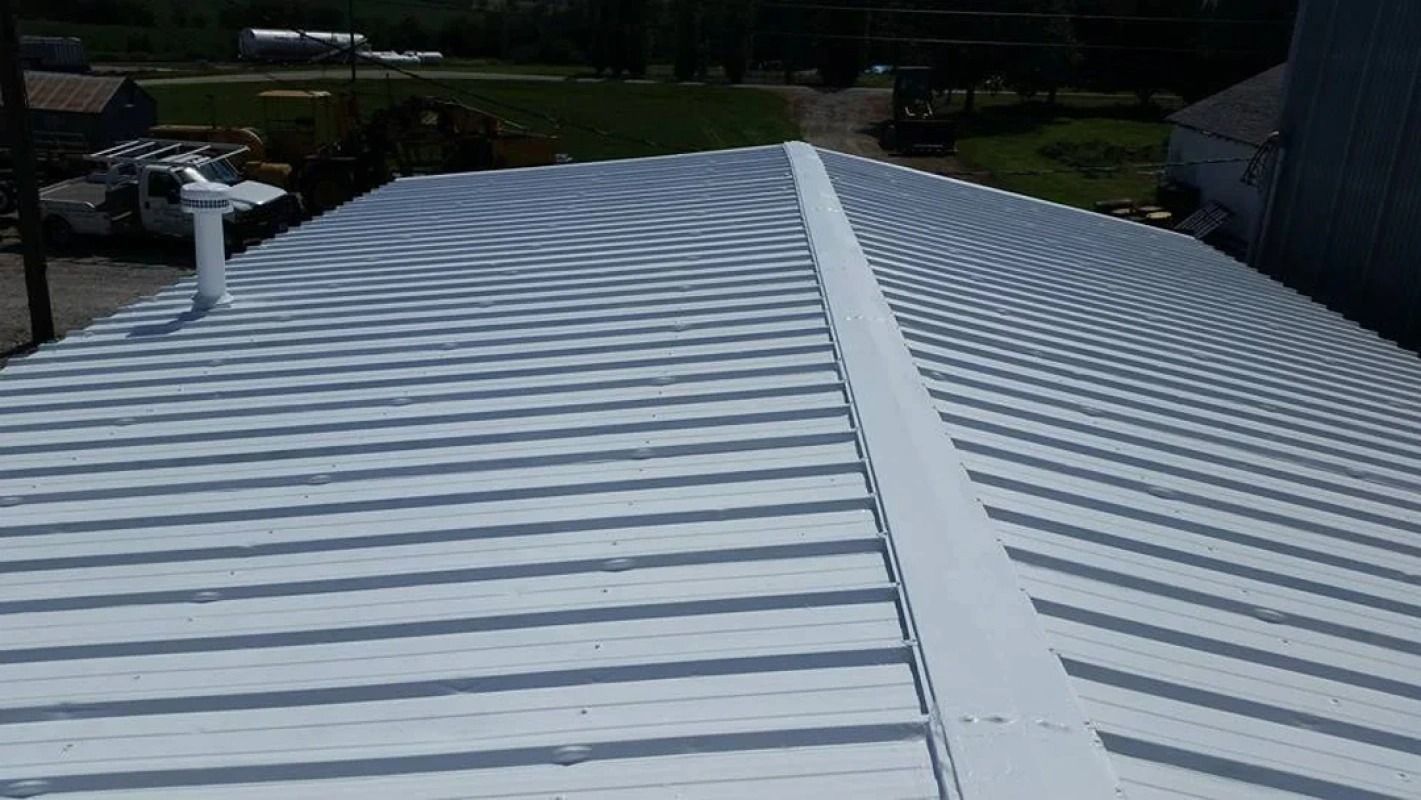 A white metal roof with a drain pipe on the side of it.