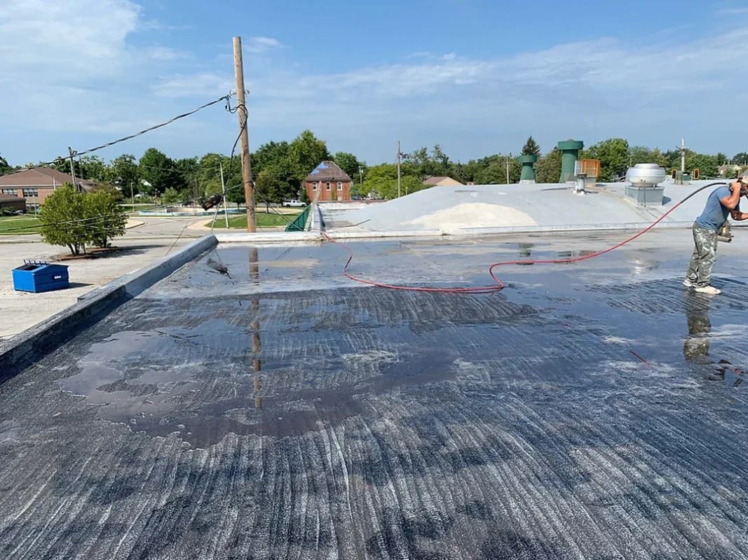 A man is cleaning the roof of a building with a hose.
