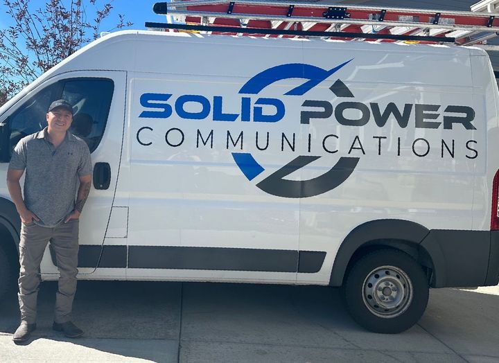 Hector Ortiz, owner of Solid Power Communications, standing next to company van | Reliable Denver electrician for all your electrical needs