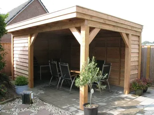 Een houten tuinhuisje met daaronder een tafel en stoelen