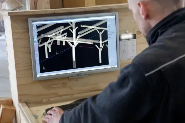 Een man kijkt naar een computerscherm met bomen erop