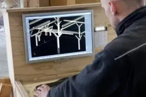 Een man zit aan een bureau en kijkt naar een computerscherm.