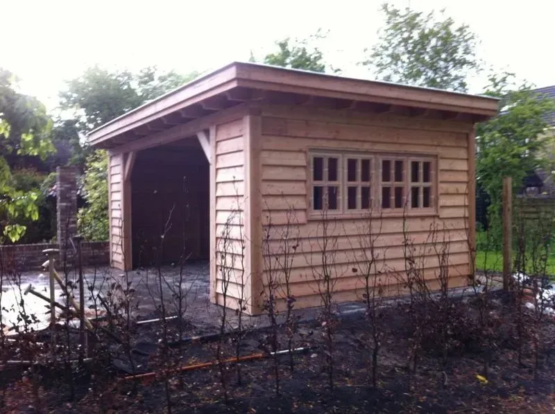 Een klein houten schuurtje met een raam aan de zijkant