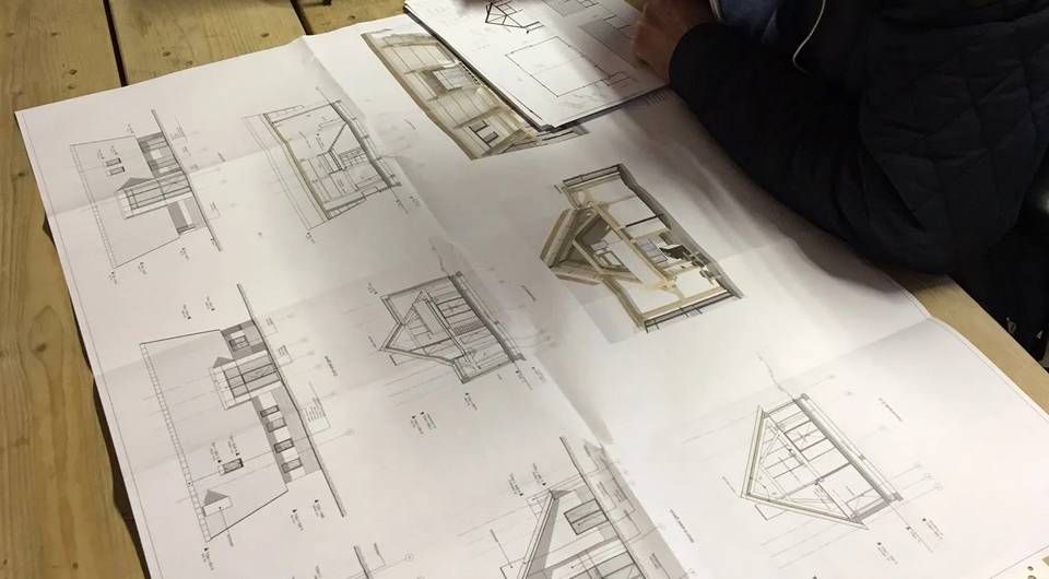 Iemand kijkt naar een tekening van een huis op een tafel.