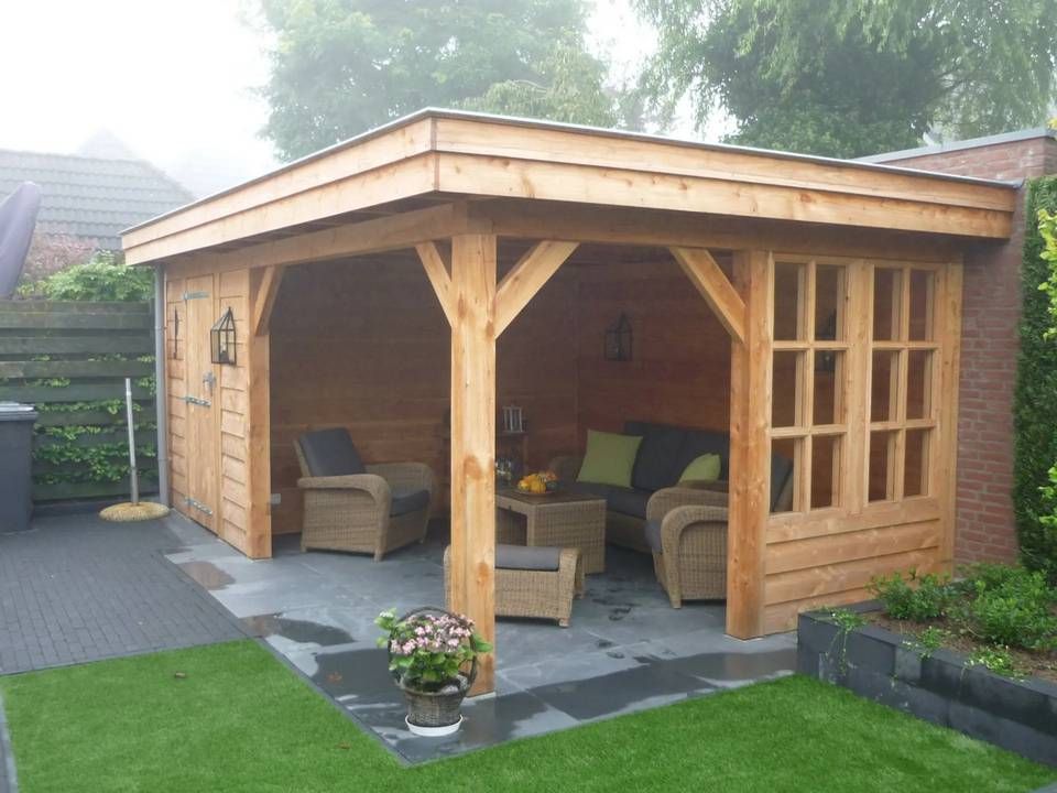 Een houten tuinhuisje met daarin rieten meubels