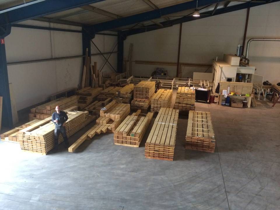 Een man staat in een magazijn vol houten pallets