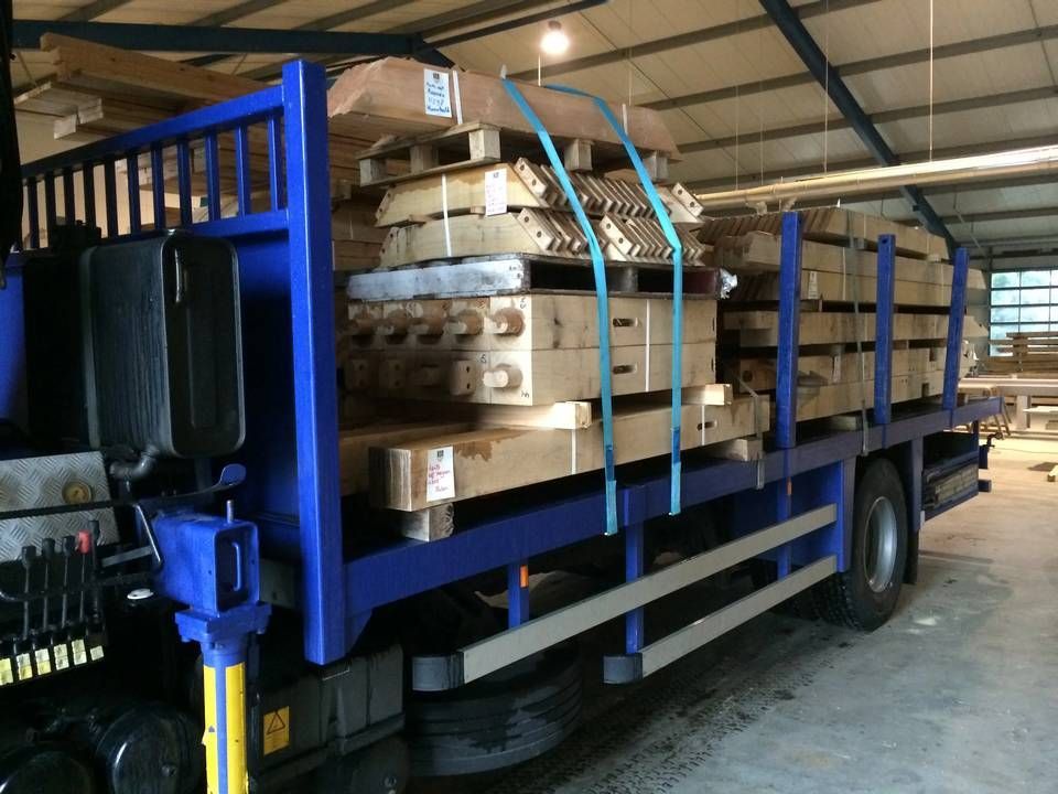 Een blauwe vrachtwagen is geladen met houten pallets in een magazijn