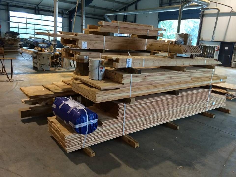 In een pakhuis wordt een stapel hout op elkaar gestapeld.