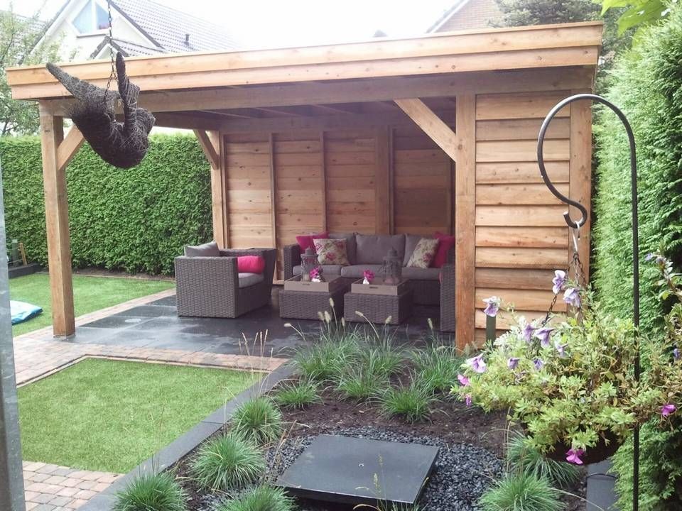 Een houten tuinhuisje met daarin een bank en stoelen