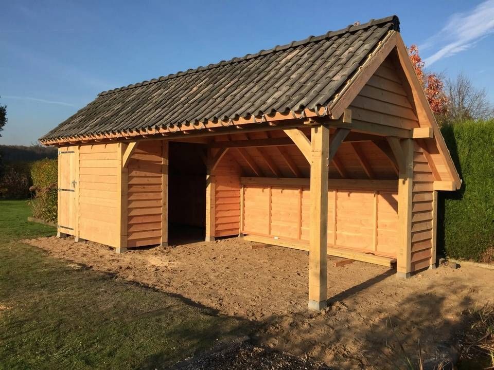 Een kleine houten schuur met een pannendak