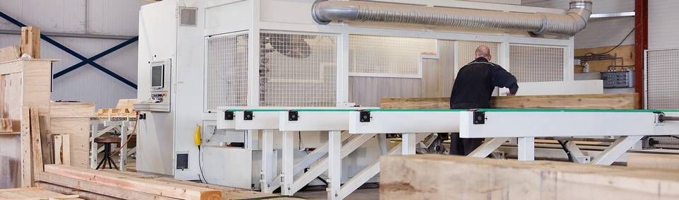 Een man staat voor een machine in een fabriek.