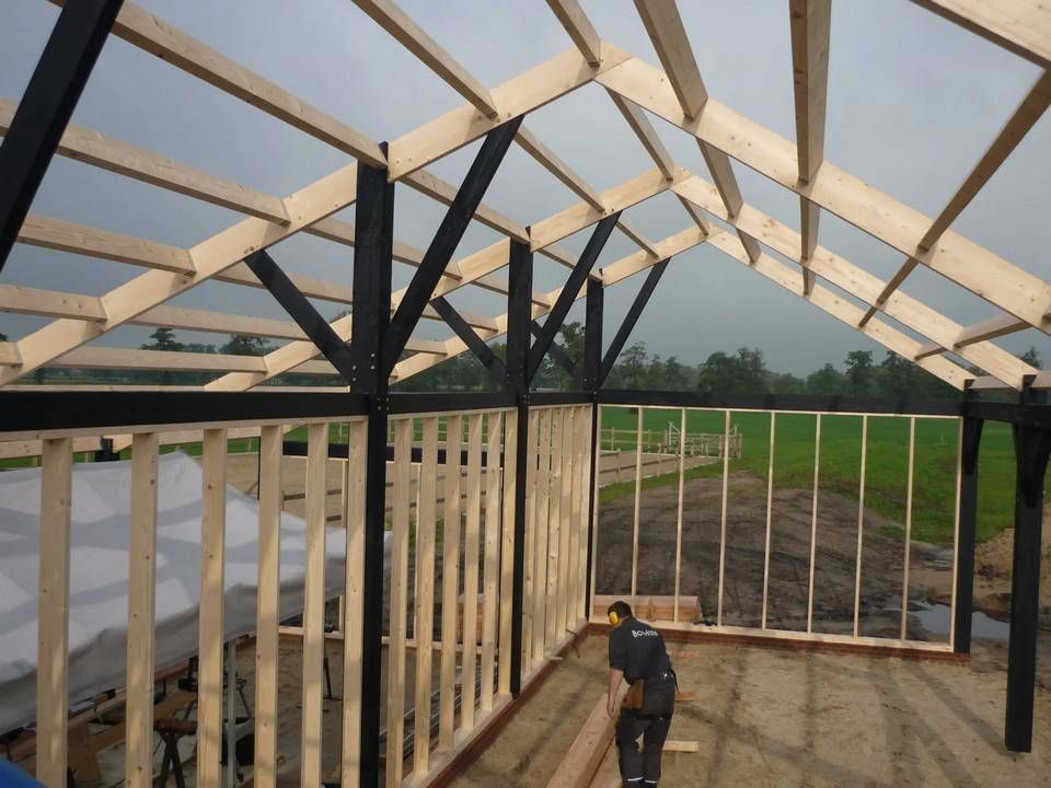 Een man staat midden in een houten constructie