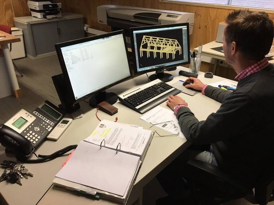 Een man zit aan een bureau en werkt op een computer