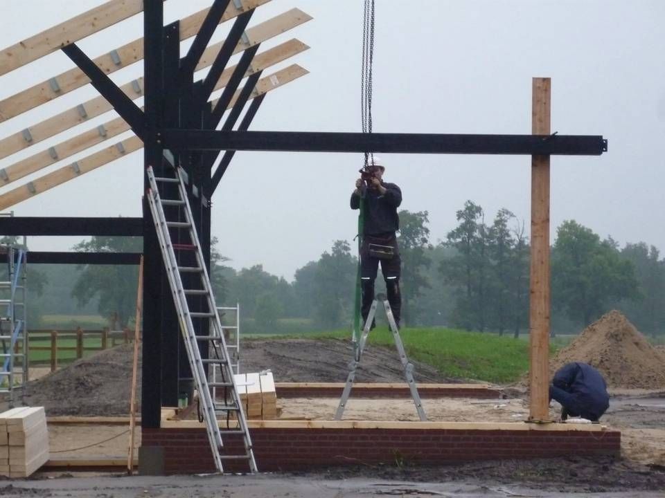 Een man staat op een ladder voor een gebouw in aanbouw