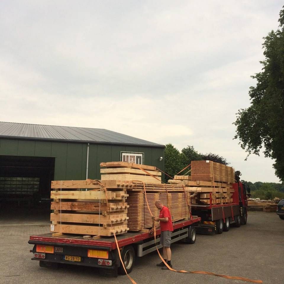Een man laadt houten pallets op een vrachtwagen