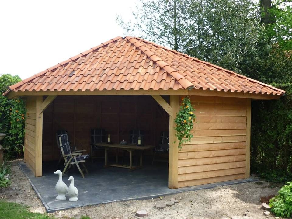 Een houten tuinhuisje met een rood pannendak