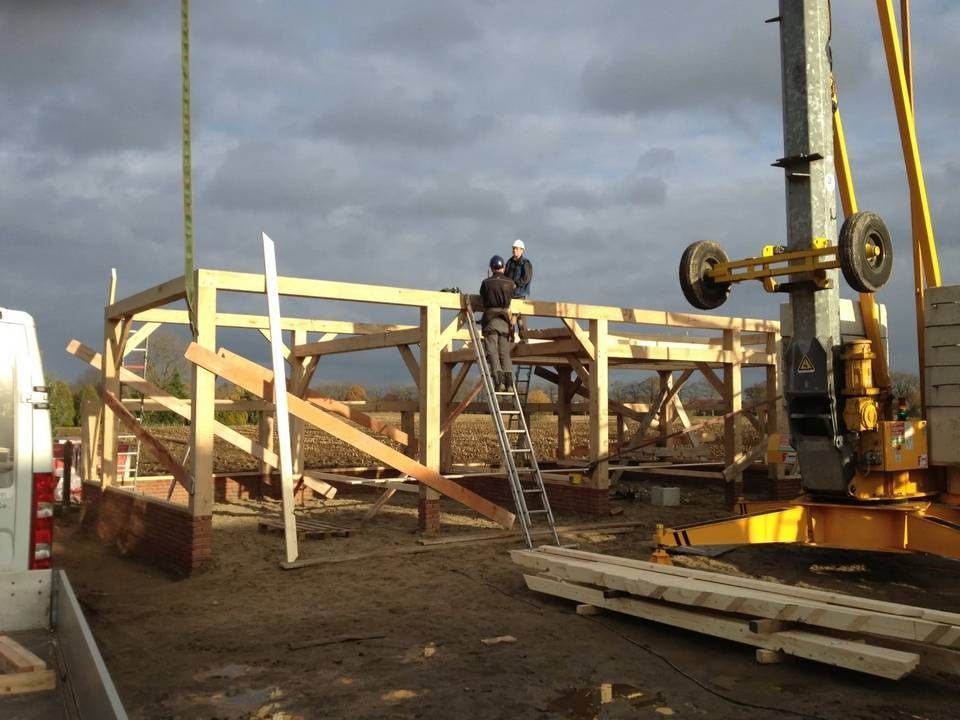 Een gele kraan tilt een houten constructie op