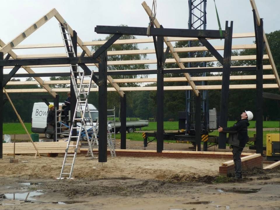 Een man met een helm staat voor een gebouw in aanbouw