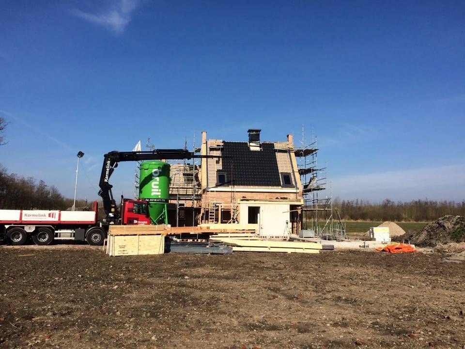 Een vrachtwagen rijdt langs een huis in aanbouw.