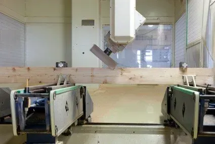 Een machine snijdt een stuk hout in een fabriek.