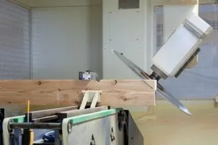 Een machine snijdt een stuk hout in een kamer.