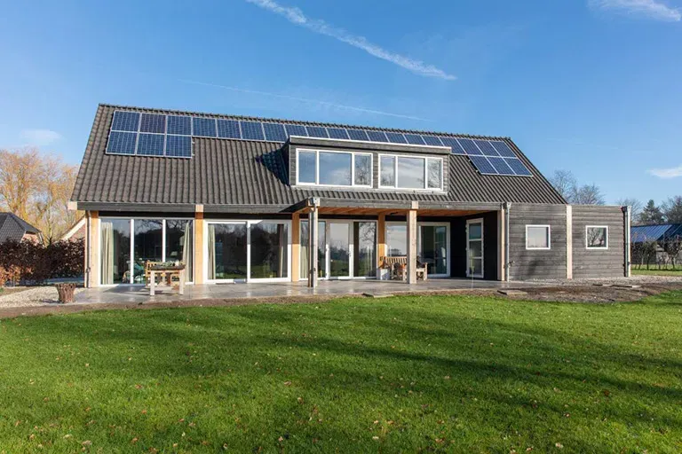 Een groot huis met veel ramen en zonnepanelen op het dak.