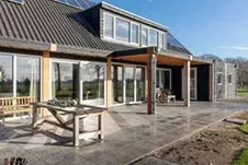 Een groot huis met een terras en een tafel ervoor.