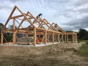 In een veld wordt een groot houten bouwwerk gebouwd.