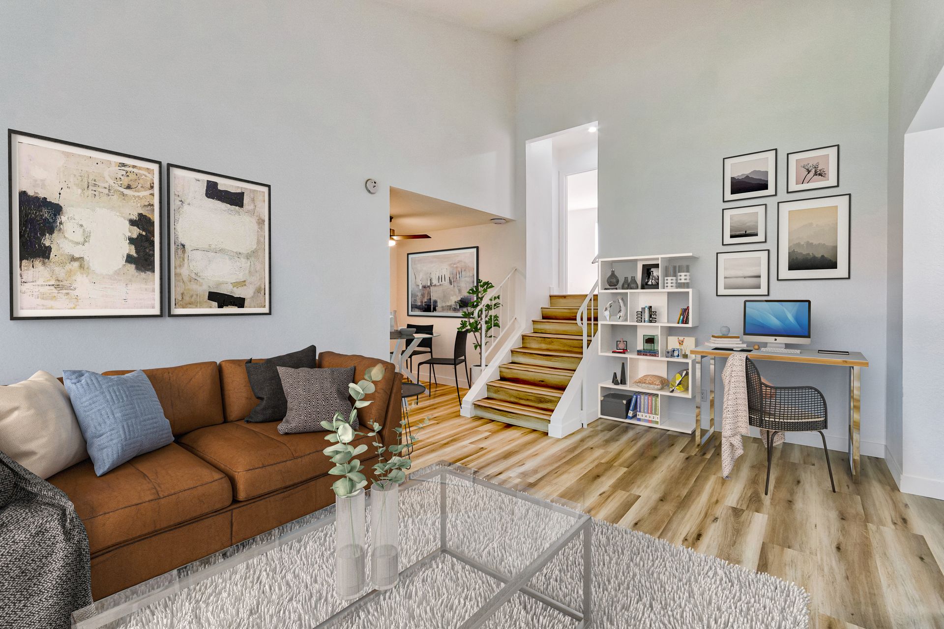 A living room with a brown couch , coffee table , desk and stairs.