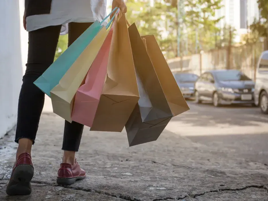 A woman is walking down a sidewalk holding a bunch of shopping bags.