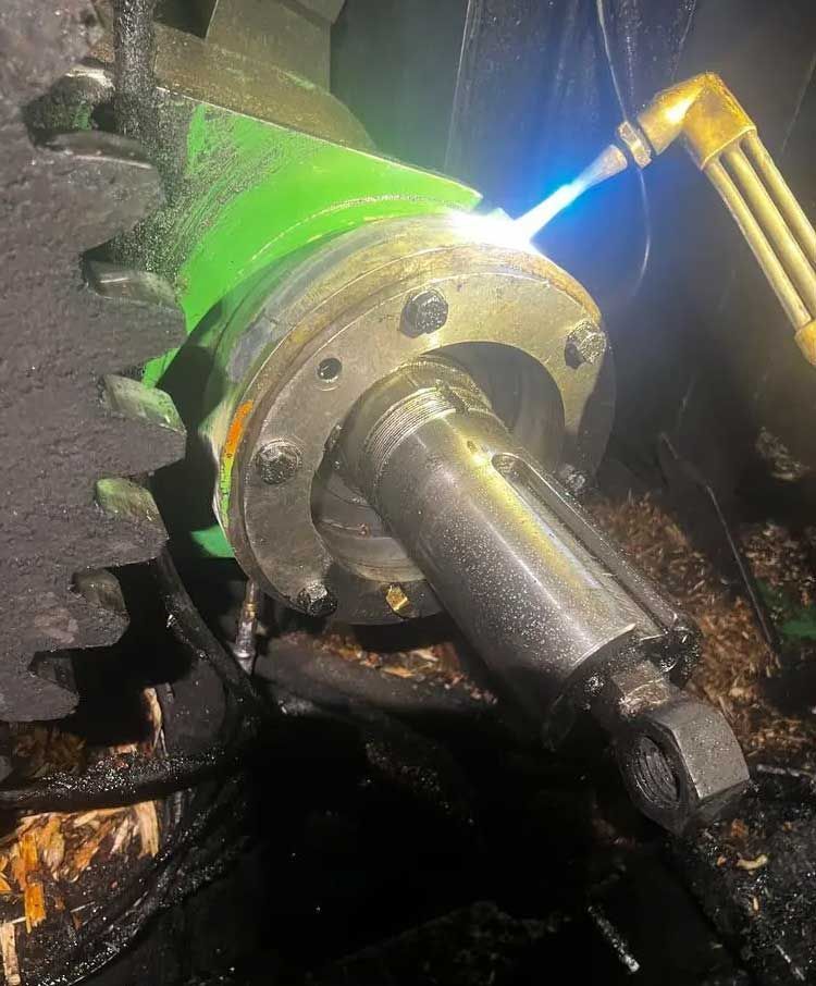 Une torche de soudage applique une flamme bleue vive sur le bord d'un assemblage mécanique métallique comportant un grand engrenage.