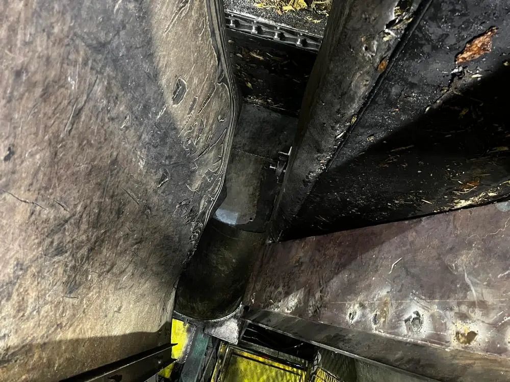 Vue en contre-plongée d'un espace métallique sombre et étroit, montrant des poutres et des rivets rouillés.