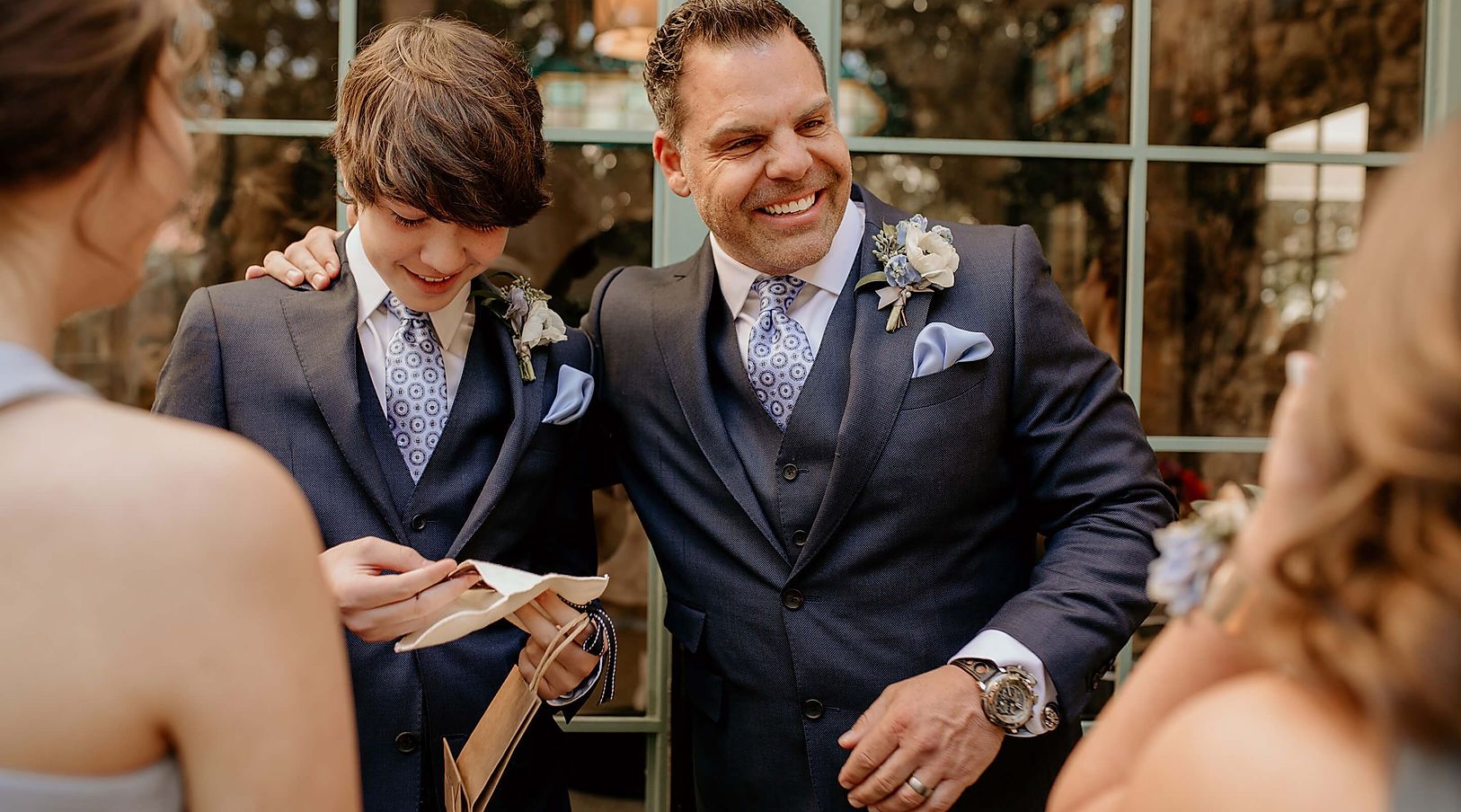 A man in a suit is standing next to a boy in a suit.